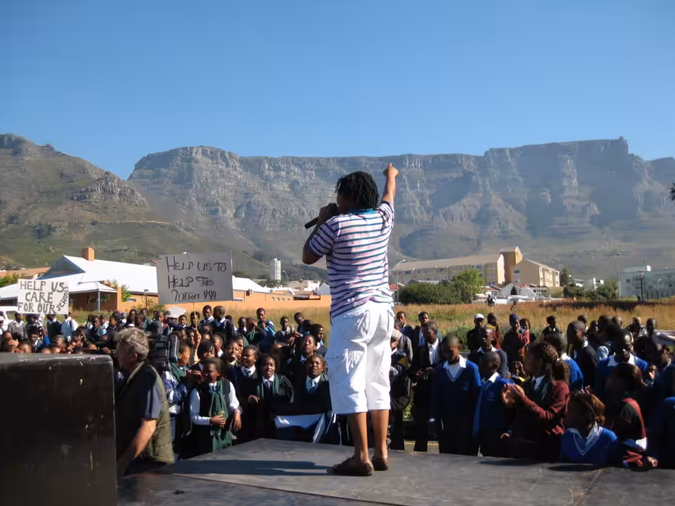 A man with a microphone addresses a crowd of school pupils at an education protest in Cape Town.