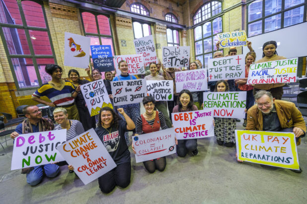 Attendees at the Activist Gathering pose in a group holding handmade signs